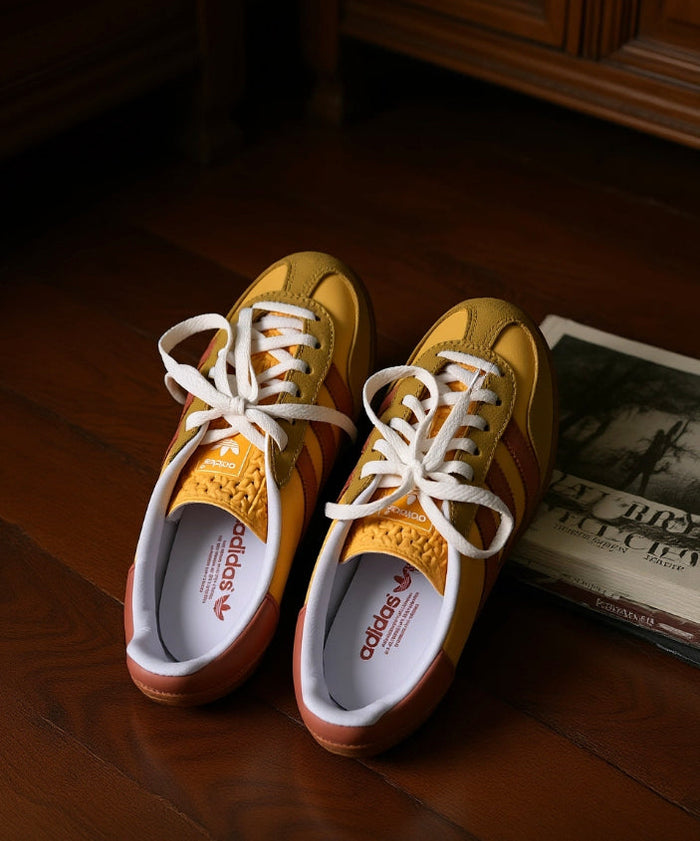 Gazelle Indoor sneakers pair, yellow uppers with pink stripes, white laces, gum sole