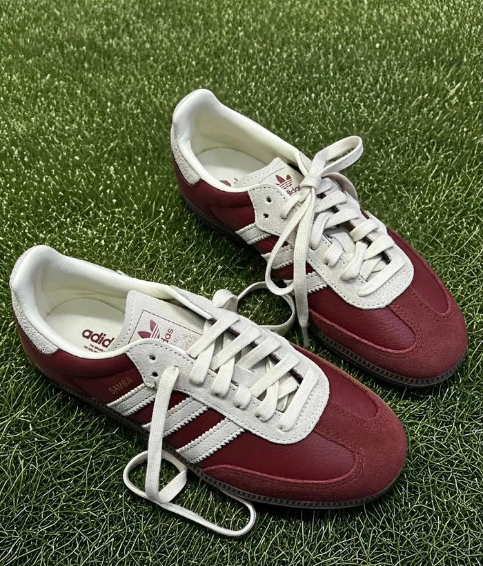 Adidas Samba OG sneakers on grass, burgundy uppers with white laces and 3-Stripes