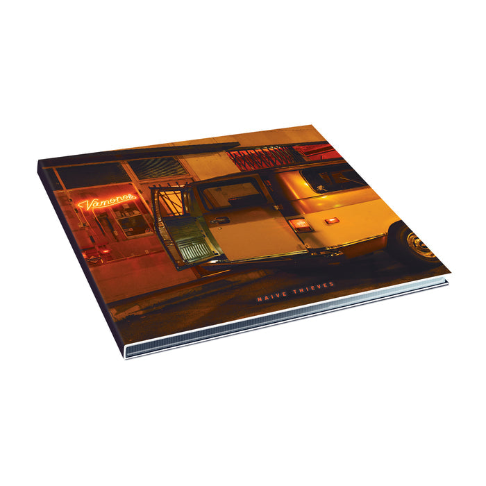 An album cover for Naive Thieves shows a yellow van with its door open, glowing inside, parked by a neon-lit building in Shakedowntown. Warm streetlights brighten the scene, with Naive Thieves visible on the cover.