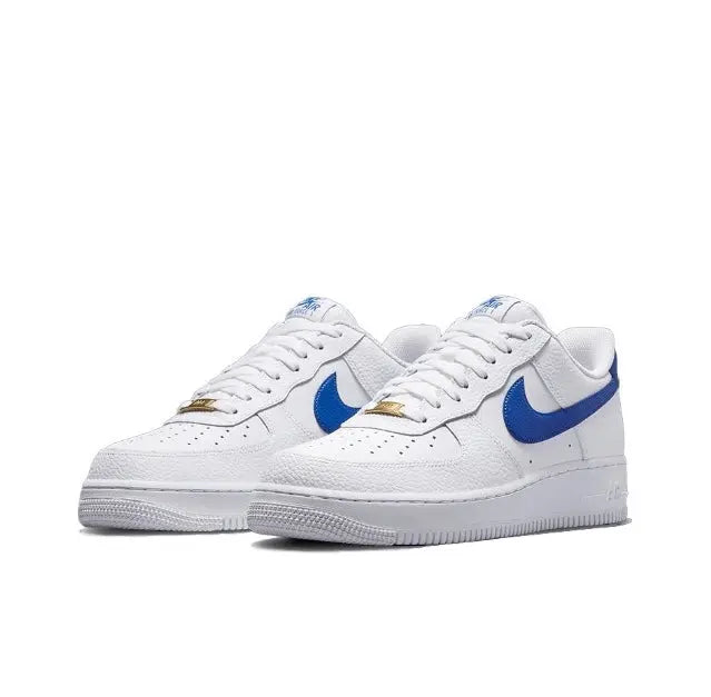 White low-top sneakers with blue swoosh, gold heel accent, and lace-up closure