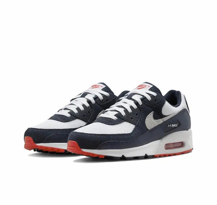 Nike Air Max 90 sneakers with white toe and grey swoosh, navy overlays, red outsole