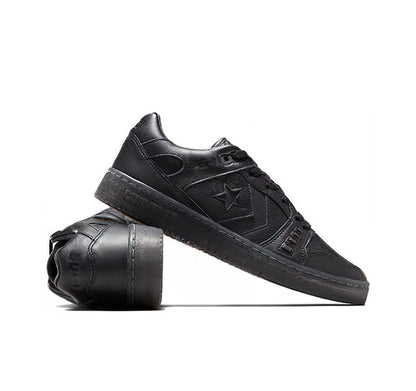 Black low-top sneakers with star logo, lace-up upper and thick rubber sole