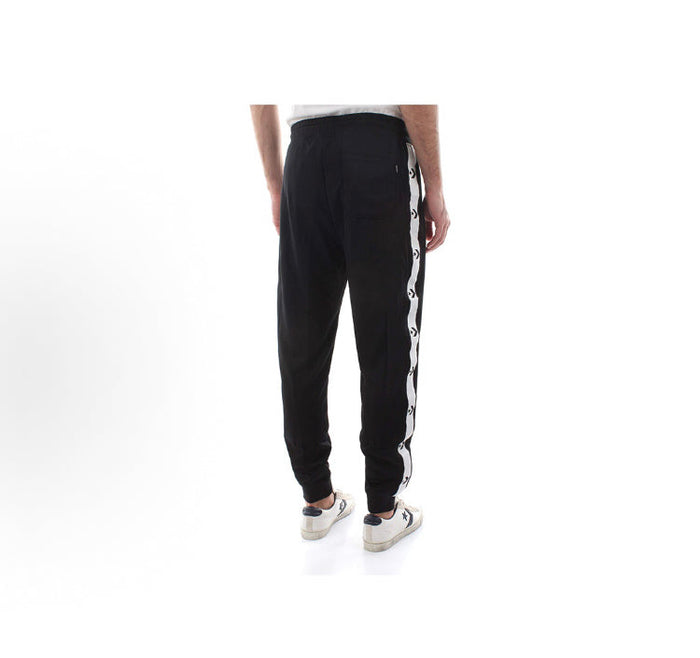 Black track pants with white side stripe panel and tapered ankle cuffs