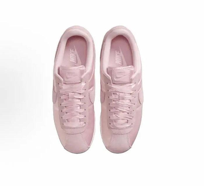 Pink Nike Cortez sneakers, pair view showing laces and cushioned tongue