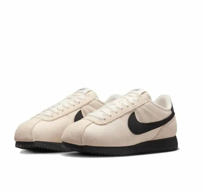 Nike Cortez sneakers, angled side view: light beige with black swoosh and sole
