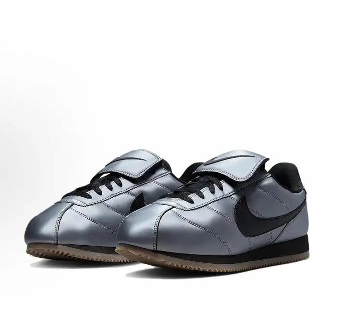 Nike low-top sneakers with grey leather uppers, black Swoosh, and lace-up fronts