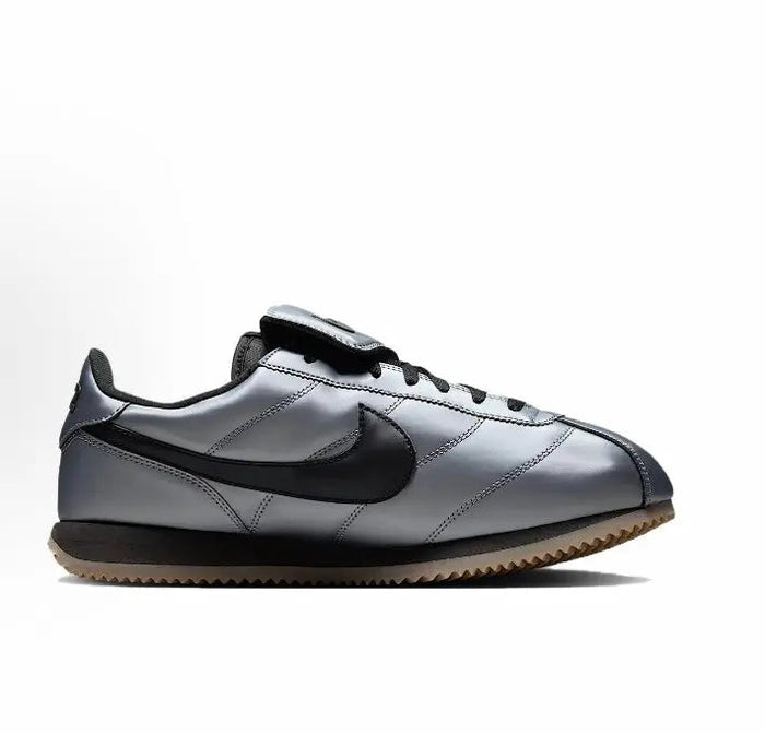 Nike low-top sneakers in grey with black Swoosh, lace-up design, and gum sole