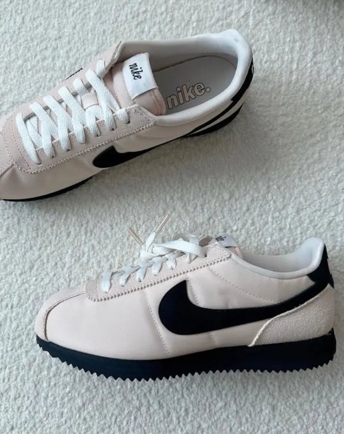 Nike Cortez sneakers on carpet: light beige with black swoosh and white laces