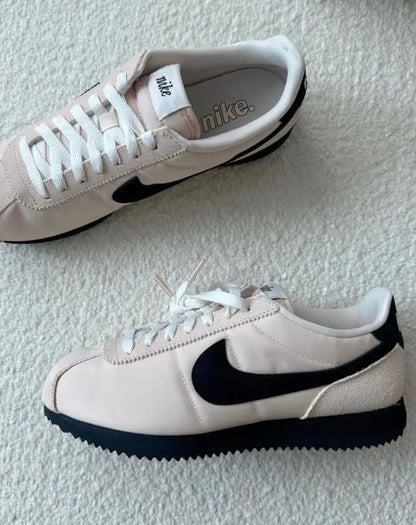 Nike Cortez sneakers on carpet: light beige with black swoosh and white laces