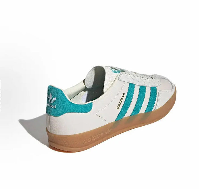 Adidas Gazelle sneakers with white leather, teal accents, and gum sole at heel