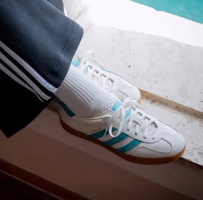 Adidas Gazelle sneakers on foot, white laces, teal stripes, and gum sole