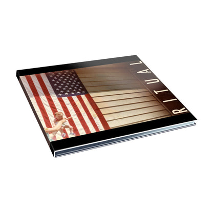 Envy On The Coast presents RITUAL, a photo book featuring a cover with a large American flag and a young child holding hands with an adult—both partly shown—walking before the flag in a scene evoking the mood of Q U I E T W O R L D.