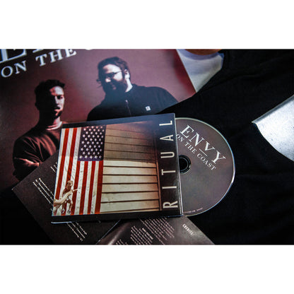 A CD by Envy On The Coast titled Ritual is partly out of its case showing an American flag on a building. Background items include hints of Ritual Flowers and a partially visible poster.