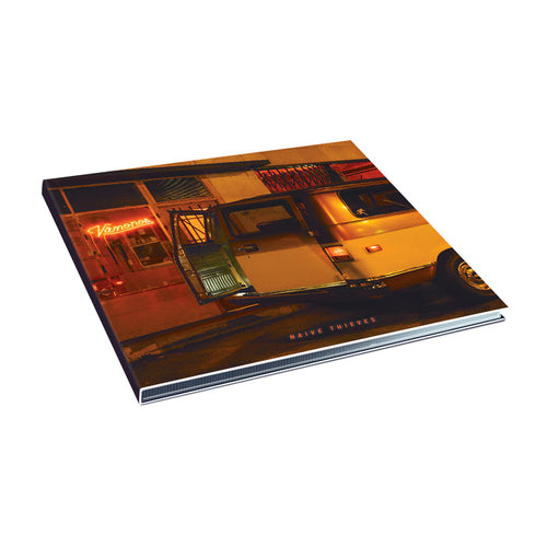 An album cover for Naive Thieves shows a yellow van with its door open, glowing inside, parked by a neon-lit building in Shakedowntown. Warm streetlights brighten the scene, with Naive Thieves visible on the cover.